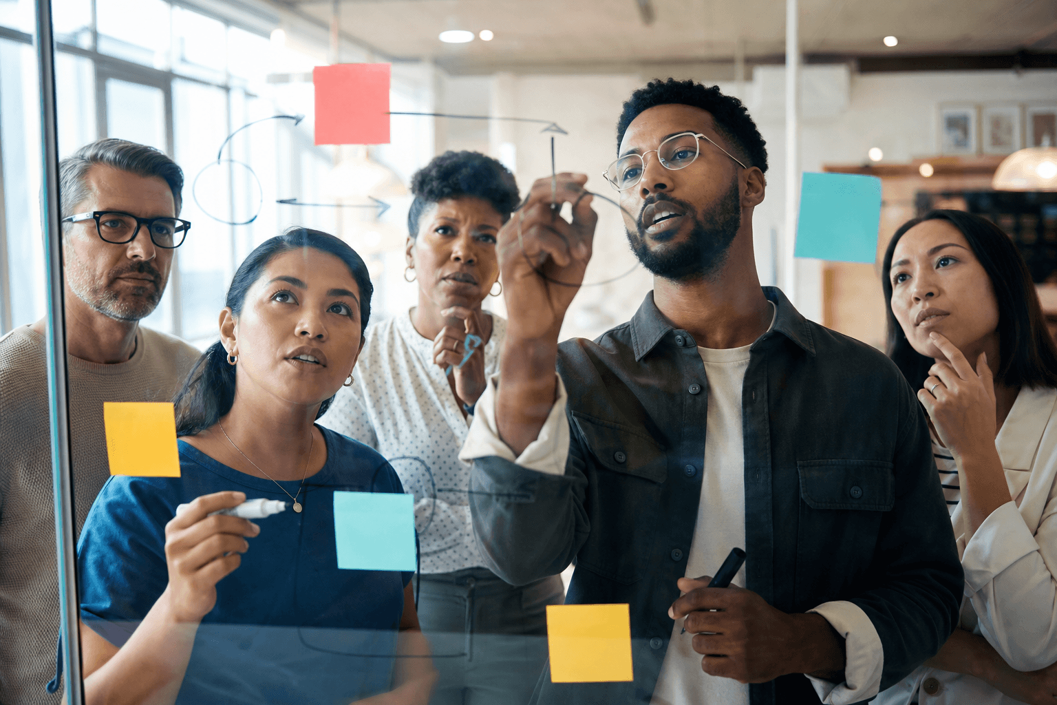 A diverse learning team examining and developing ideas together through a transparent glass surface